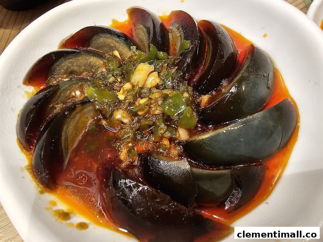 A close-up of sliced century eggs served with a vibrant spicy green chili and garlic sauce.