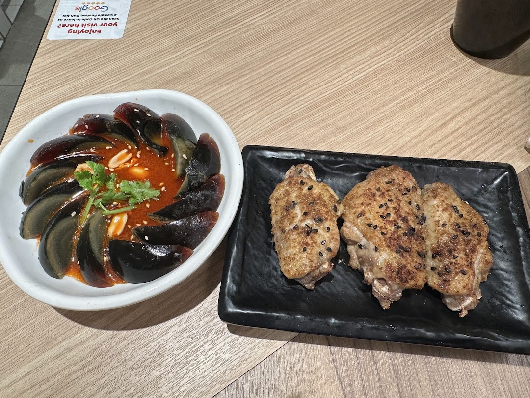 A close-up of two popular side dishes: century eggs in chili sauce and roasted chicken wings.
