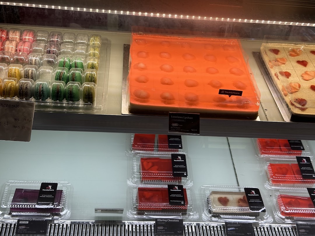 A vibrant display of colorful macarons and exquisite jelly cakes in a dessert shop.