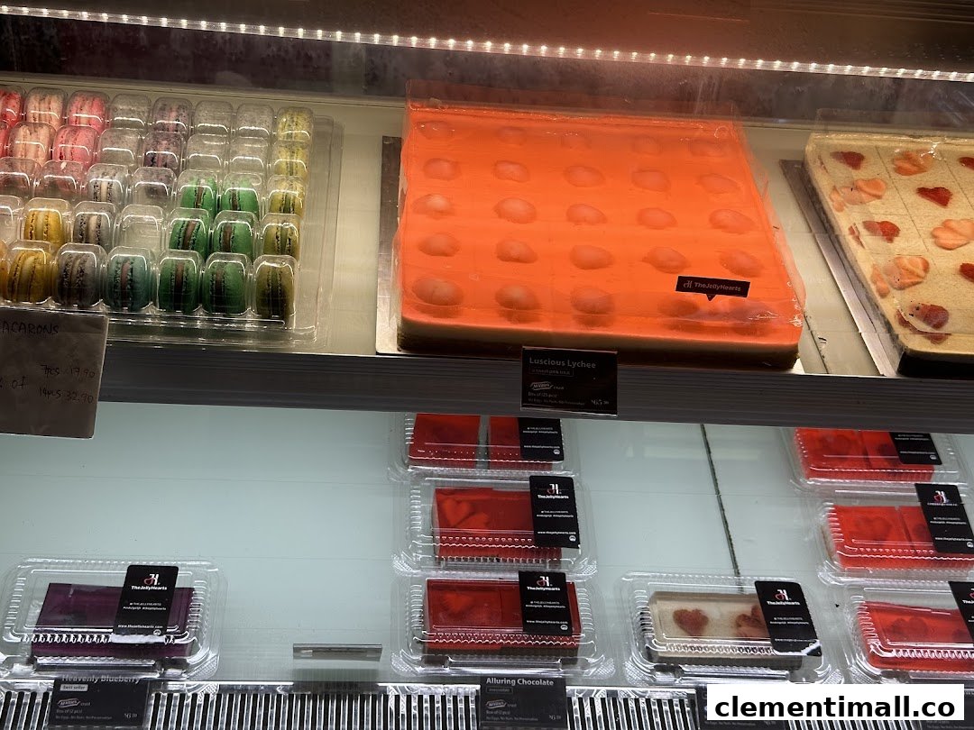 A vibrant display of colorful macarons and exquisite jelly cakes in a dessert shop.