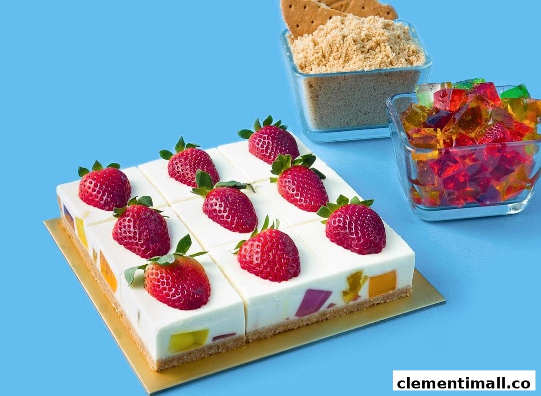 Colorful jelly cheesecake squares topped with fresh strawberries, with ingredients nearby.