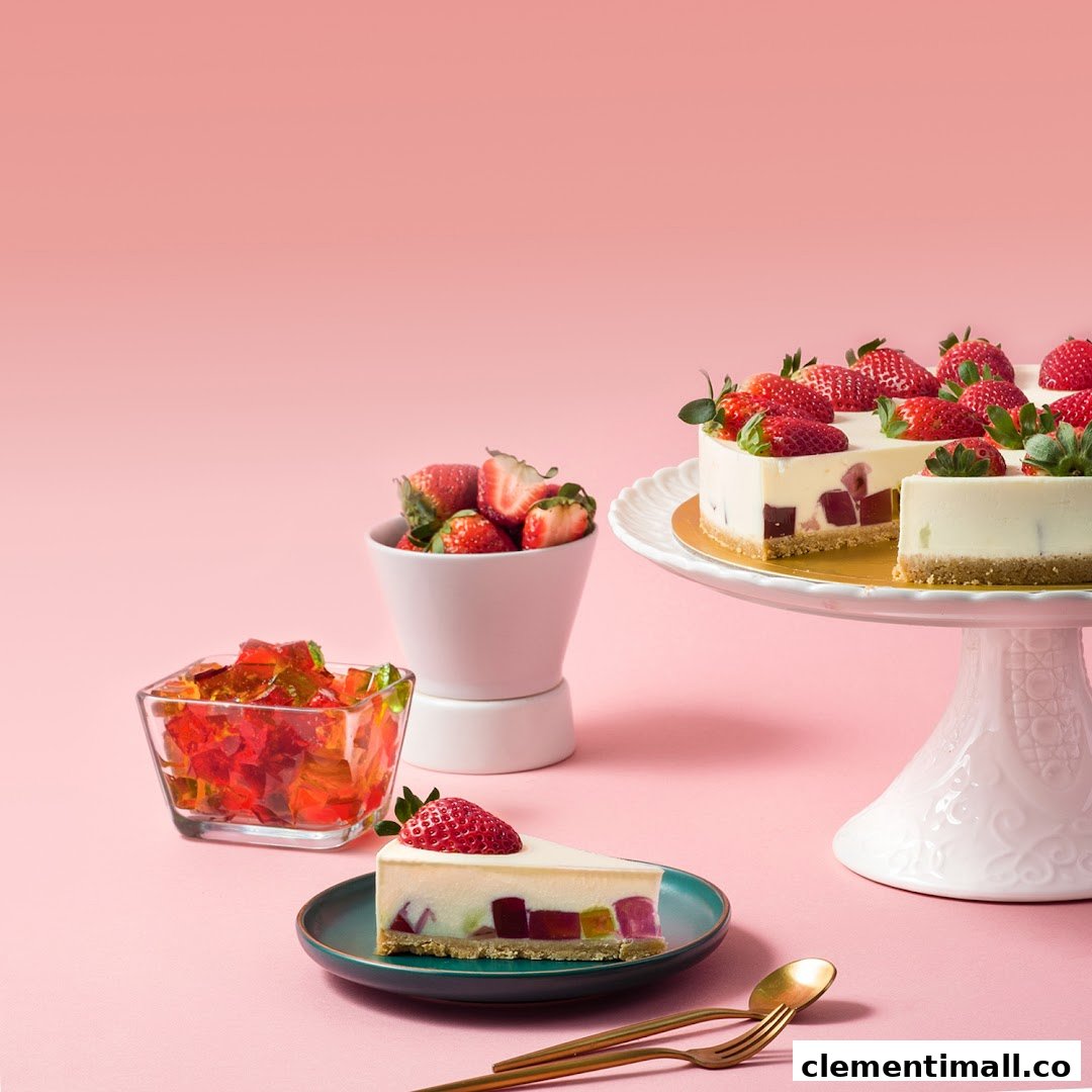 A vibrant image showcasing a cheesecake with colorful jelly cubes and fresh strawberries on a pink background.