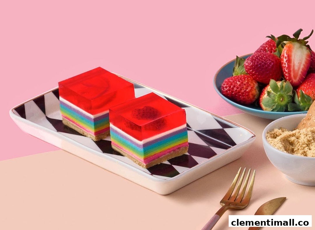 Two vibrant rainbow jelly cakes with fresh strawberries on a checkered plate.