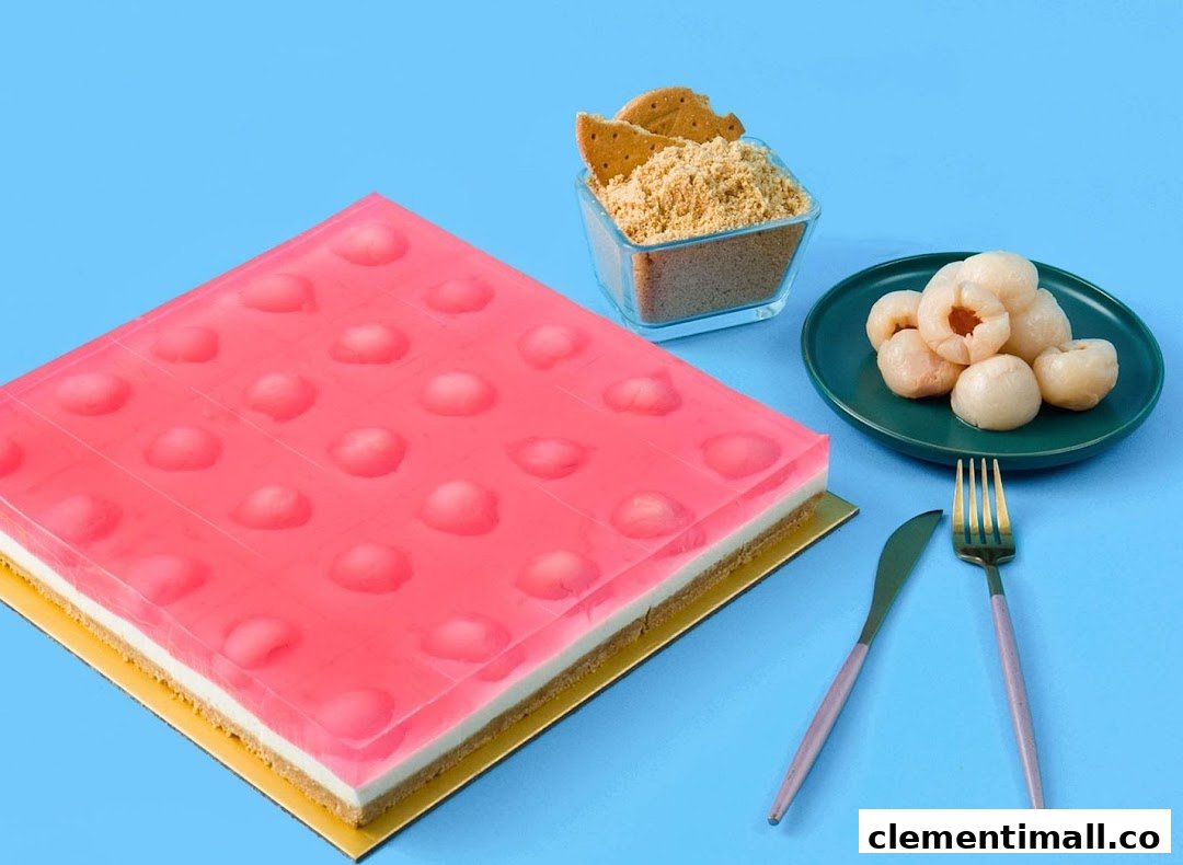 A vibrant pink jelly cake with lychee pieces, served with crushed biscuits and fresh lychees.