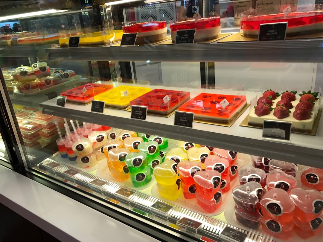 A vibrant display chiller showcasing a variety of colorful jelly cakes and individual jelly cups.