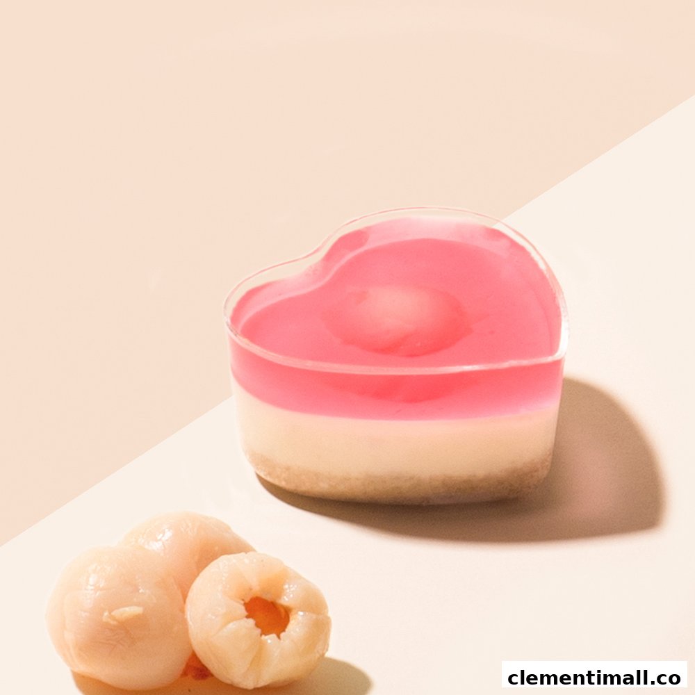 A heart-shaped dessert with pink jelly and a creamy base, accompanied by fresh lychees.