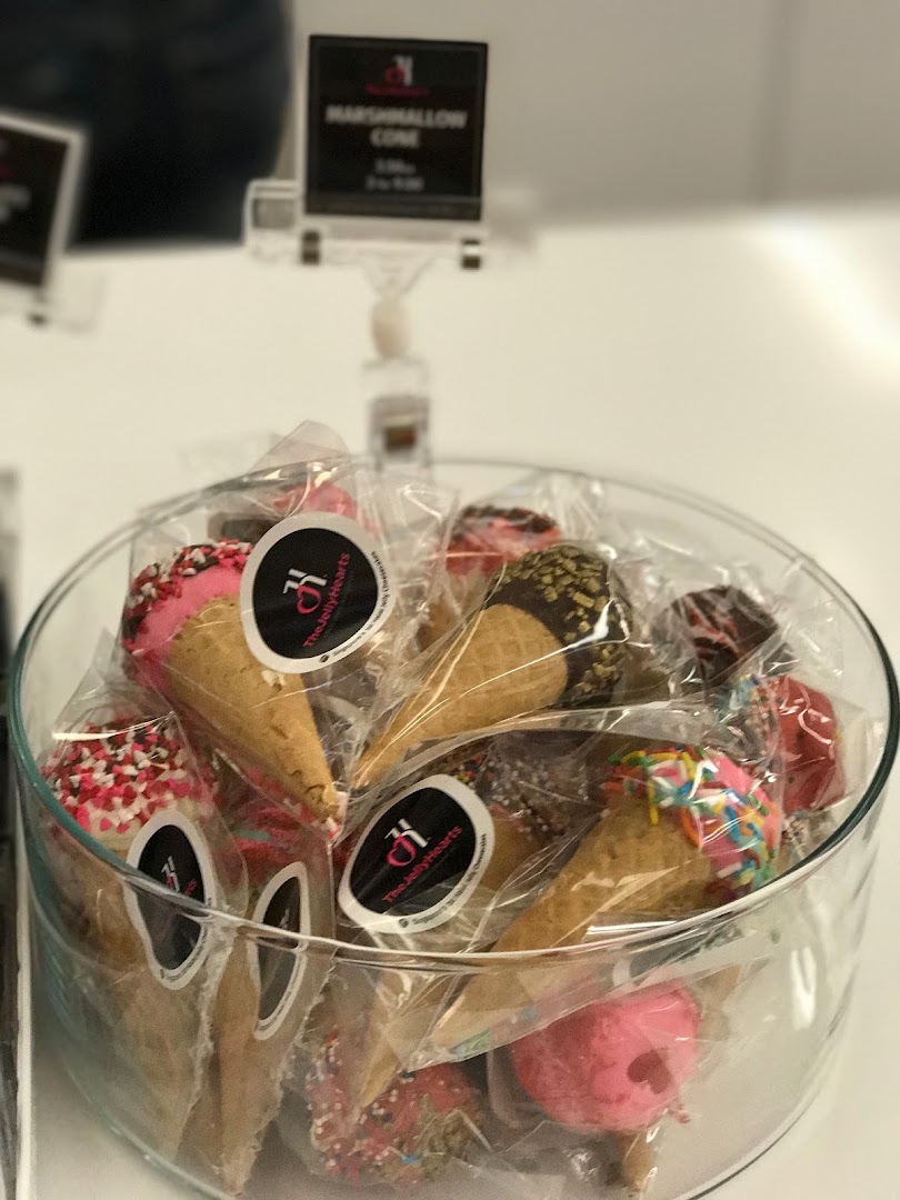 A clear glass bowl filled with individually wrapped, colorful marshmallow cones from The JellyHearts.