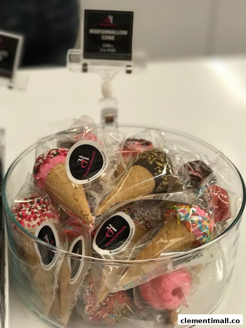 A clear glass bowl filled with individually wrapped, colorful marshmallow cones from The JellyHearts.