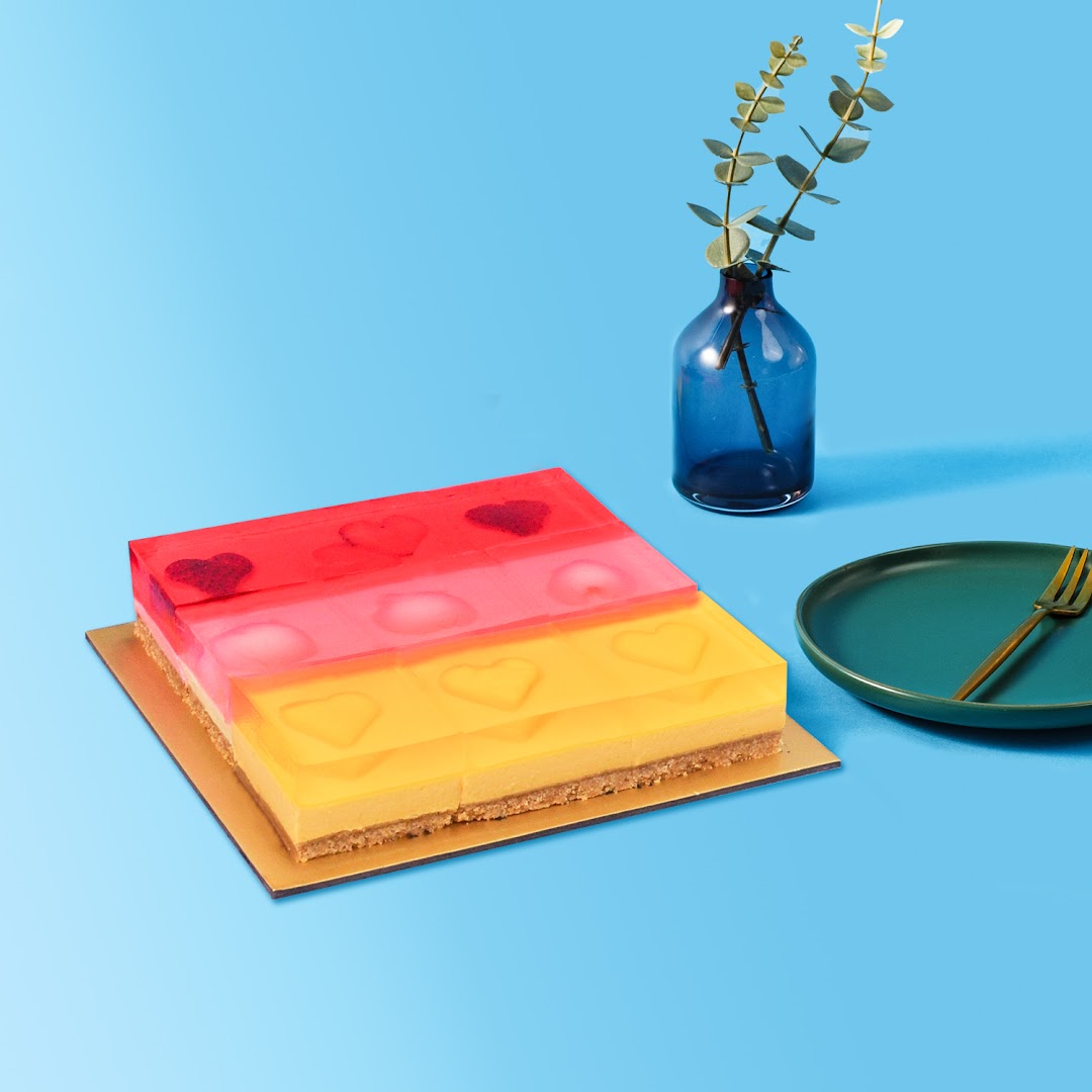 A vibrant, multi-layered jelly cake with heart designs, presented on a blue background.