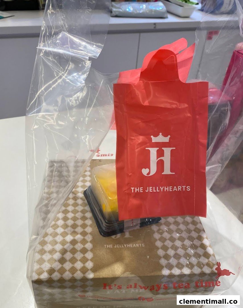 A clear plastic bag containing a branded box and a small dessert from The JellyHearts.