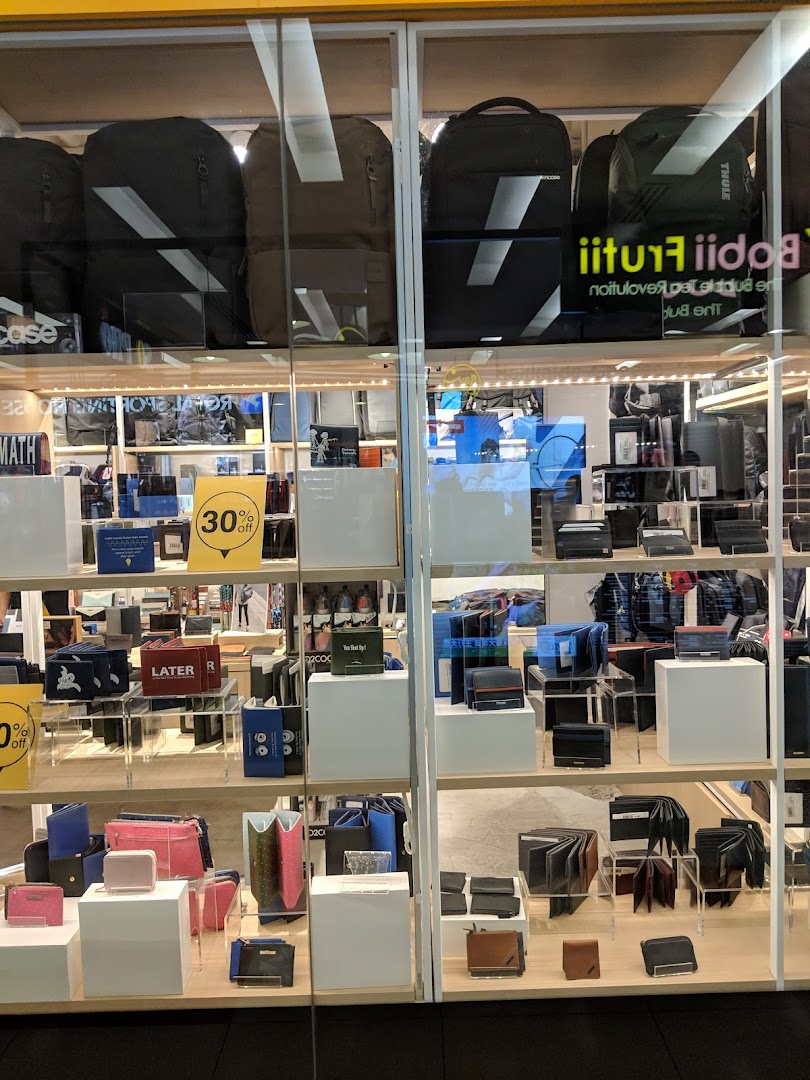 The Wallet Shop's storefront displays a wide array of wallets, bags, and accessories, including backpacks and small leather goods.