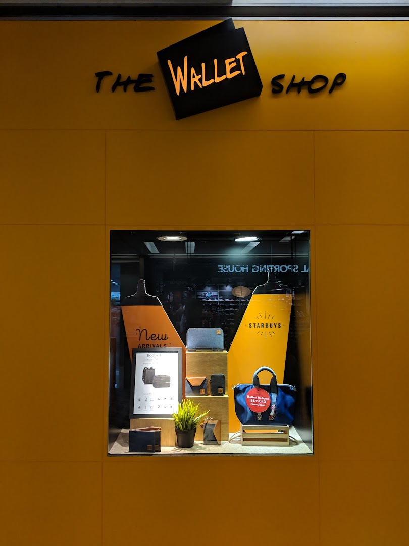 The vibrant yellow storefront of The Wallet Shop, showcasing a display window with wallets and bags.