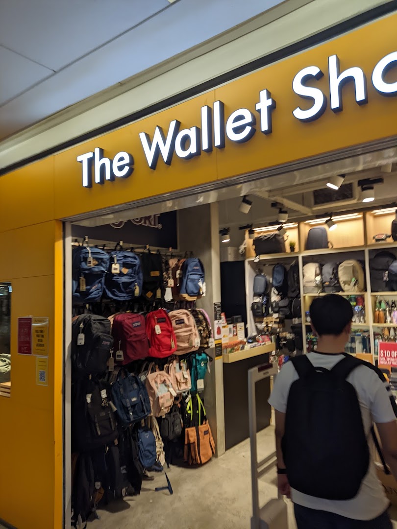 The storefront of The Wallet Shop, showcasing a wide array of bags and wallets, with a customer entering.