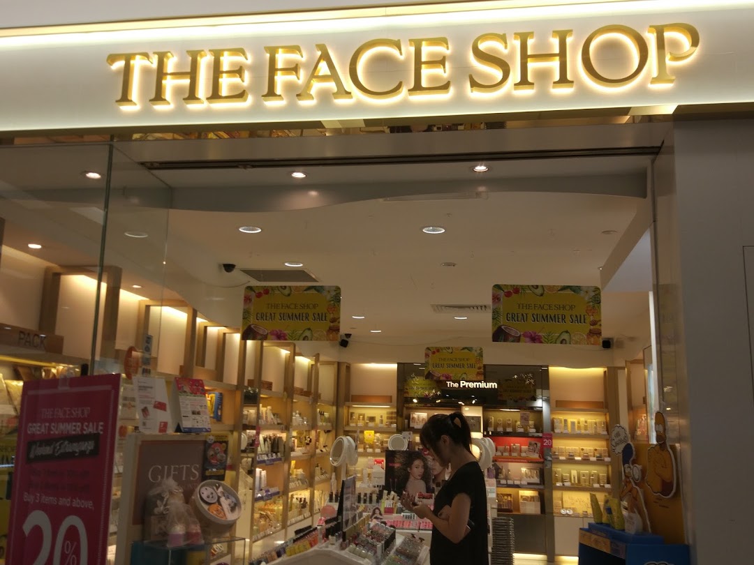 The bright entrance of THEFACESHOP, featuring its logo, interior displays, and a customer browsing products.