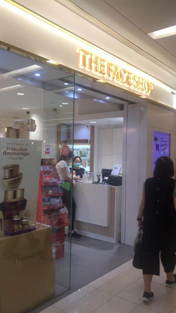 The entrance of THEFACESHOP, showcasing its bright interior, product displays, and a staff member.