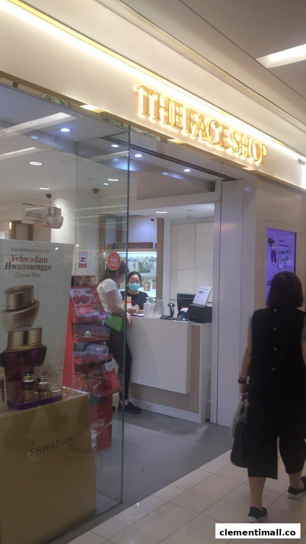 The entrance of THEFACESHOP, showcasing its bright interior, product displays, and a staff member.