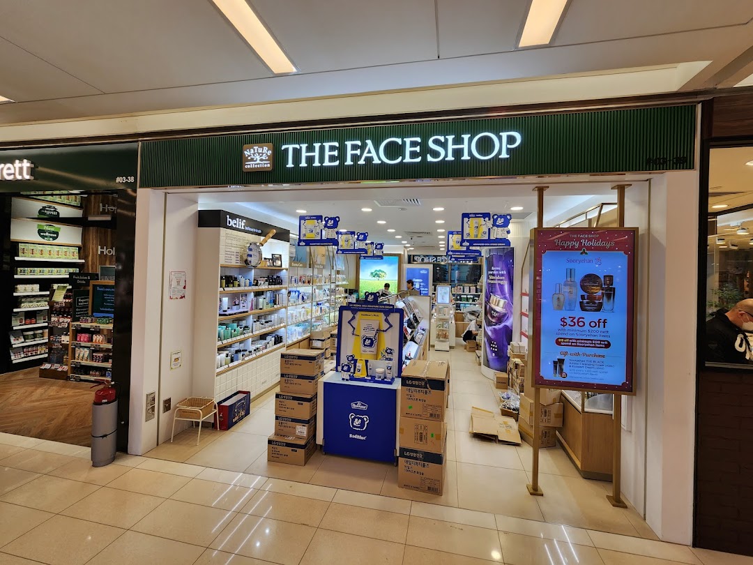 The storefront of THEFACESHOP, showcasing its entrance and a holiday promotion.