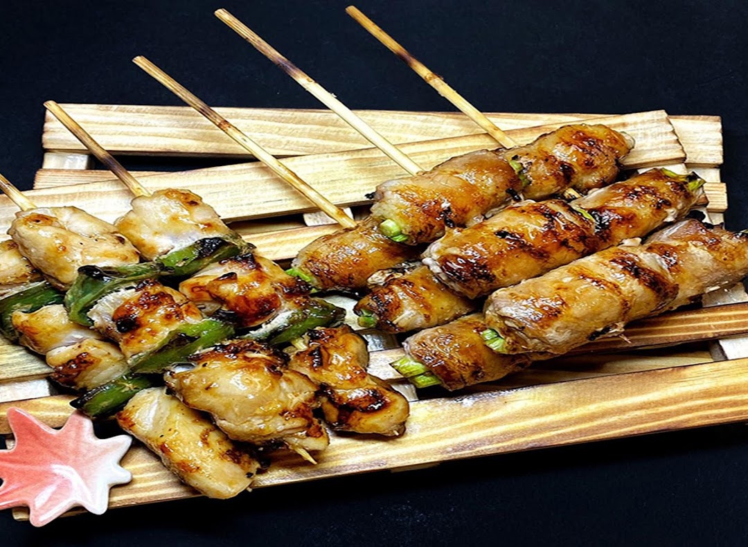Delicious grilled skewers, including chicken and vegetable-wrapped meat, served on a rustic wooden tray.