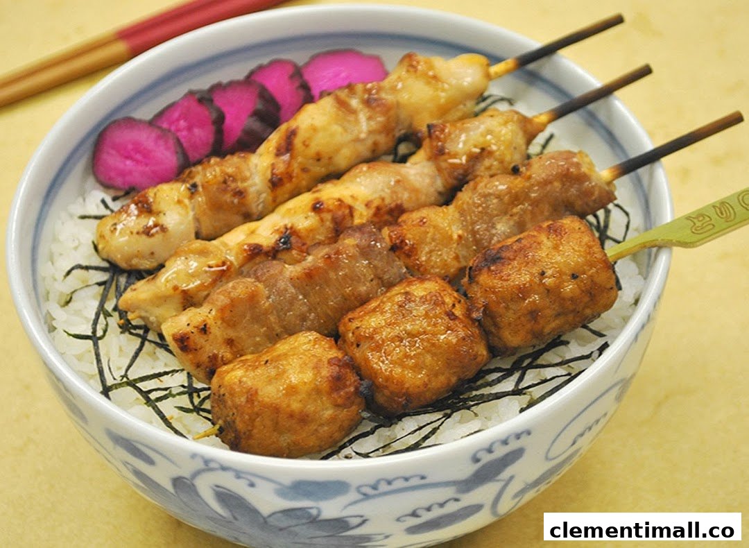 A bowl of rice topped with various grilled yakitori skewers and pickled vegetables.