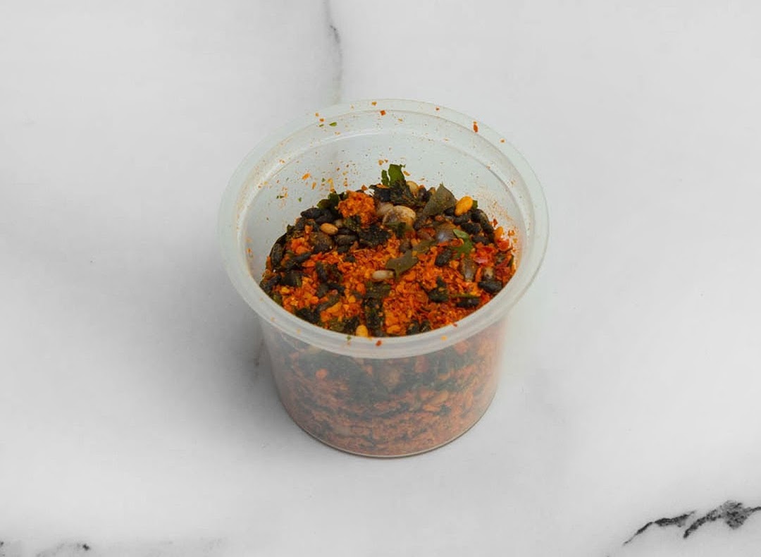 A clear plastic container filled with a vibrant mix of spices and dried ingredients.