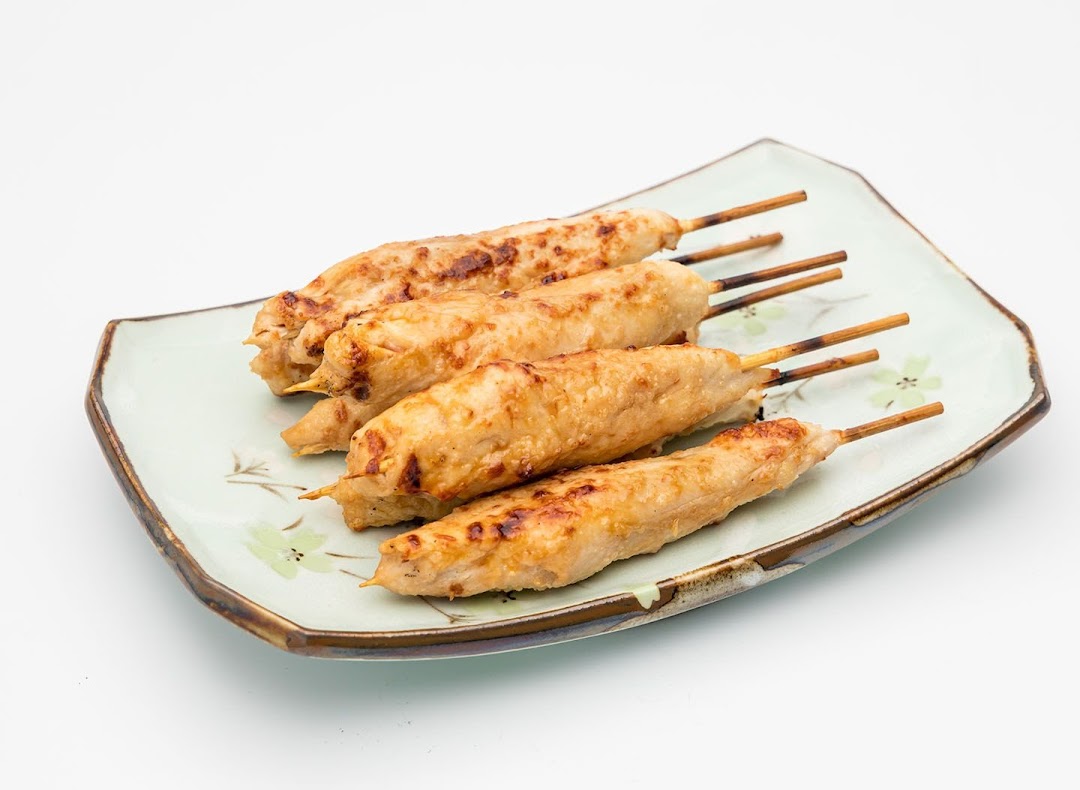 Five grilled chicken skewers with a slight char, served on a light green patterned plate.
