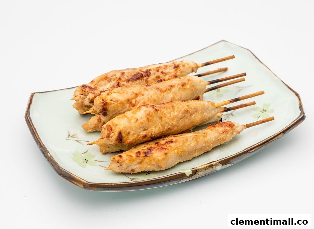 Five grilled chicken skewers with a slight char, served on a light green patterned plate.