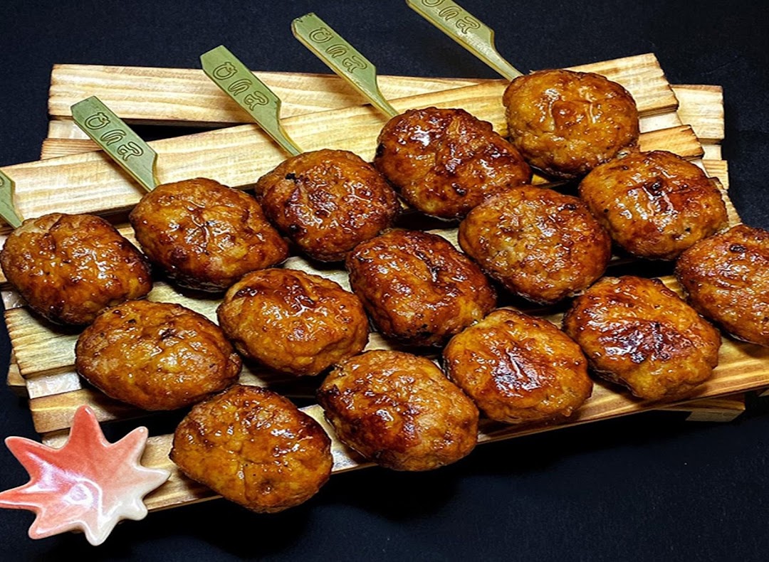 Delicious glazed meatballs on skewers arranged on a wooden tray, with a small star-shaped dish.