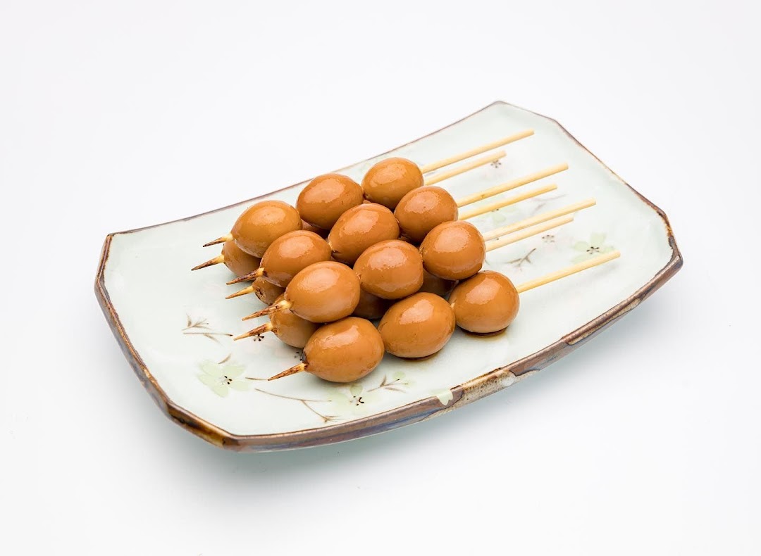 A plate of savory brown quail eggs on wooden skewers, ready to eat.