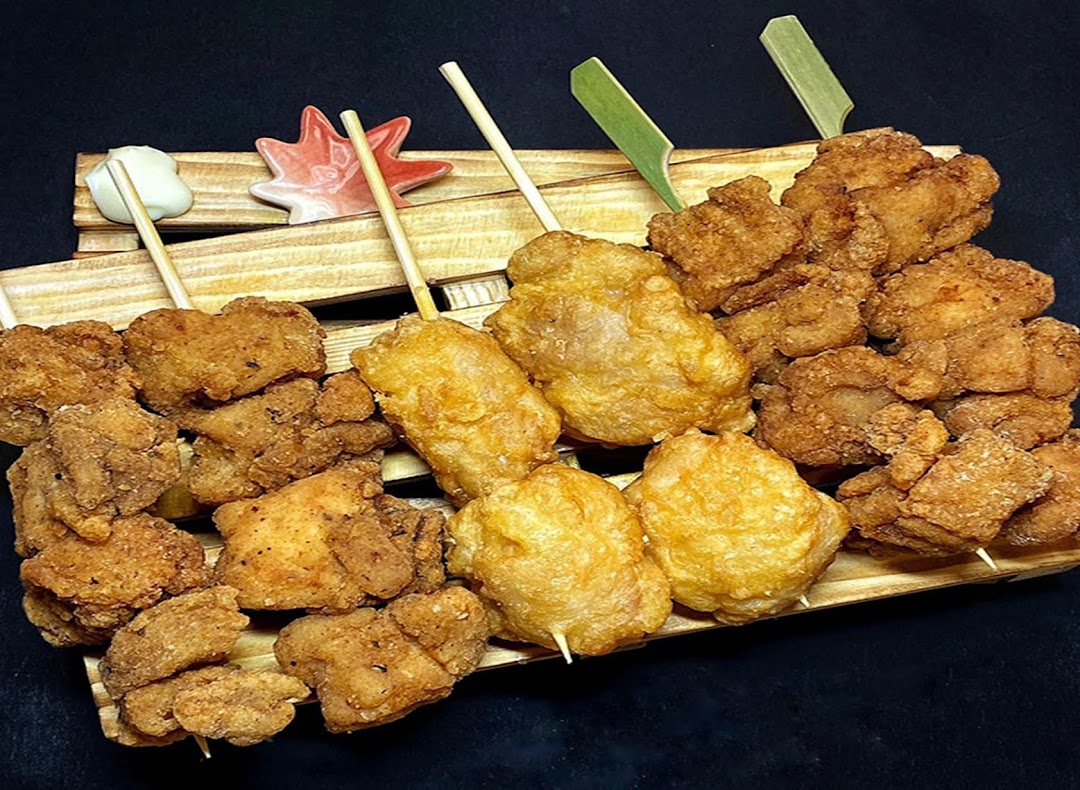 A wooden tray filled with various golden-brown fried chicken pieces and skewers, ready to eat.