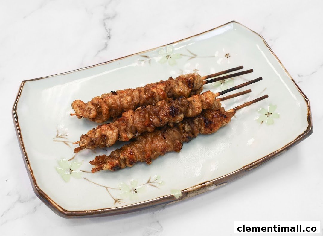 Three grilled meat skewers are presented on a decorative white plate with floral patterns.