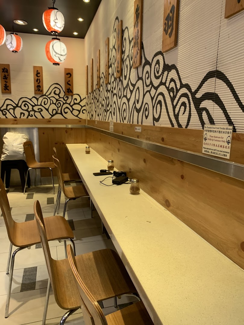 A cozy interior view of TORI-Q, featuring counter seating, wooden accents, and Japanese-inspired decor.