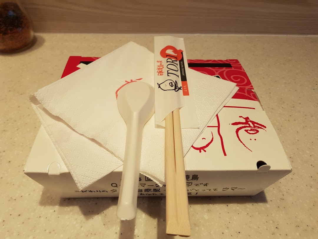 A TORI-Q takeaway box with chopsticks, spoon, and napkin, ready for a delicious meal.