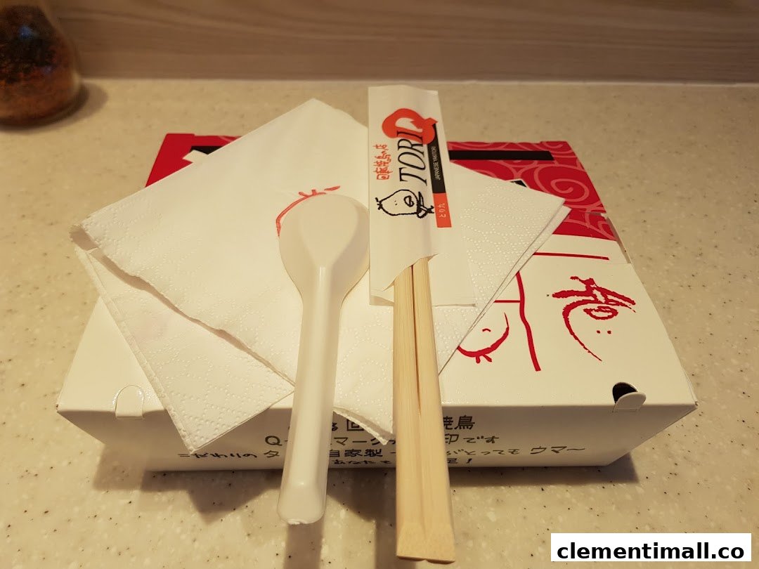 A TORI-Q takeaway box with chopsticks, spoon, and napkin, ready for a delicious meal.