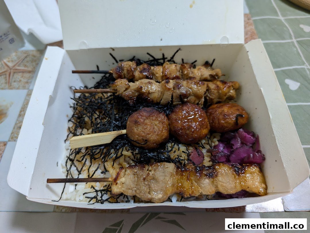 A delicious bento box featuring grilled skewers, meatballs, rice, and pickled vegetables.