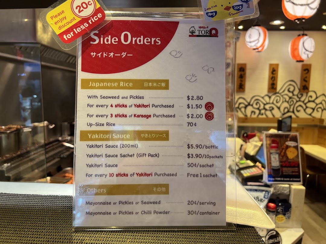 A detailed menu board displaying side orders, rice, and sauce options with prices at TORI-Q.