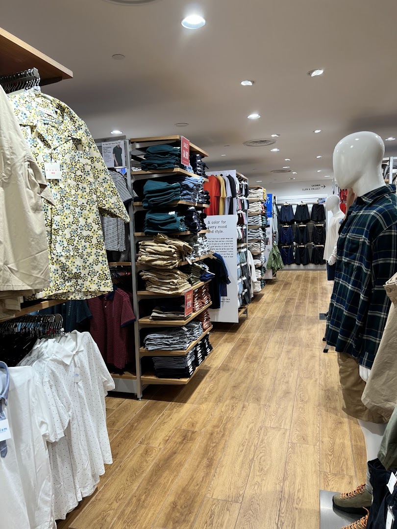 An interior view of UNIQLO, showcasing various clothing displays and mannequins in a well-lit retail space.