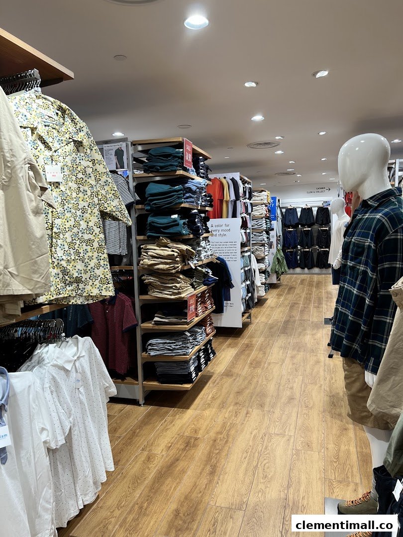 An interior view of UNIQLO, showcasing various clothing displays and mannequins in a well-lit retail space.