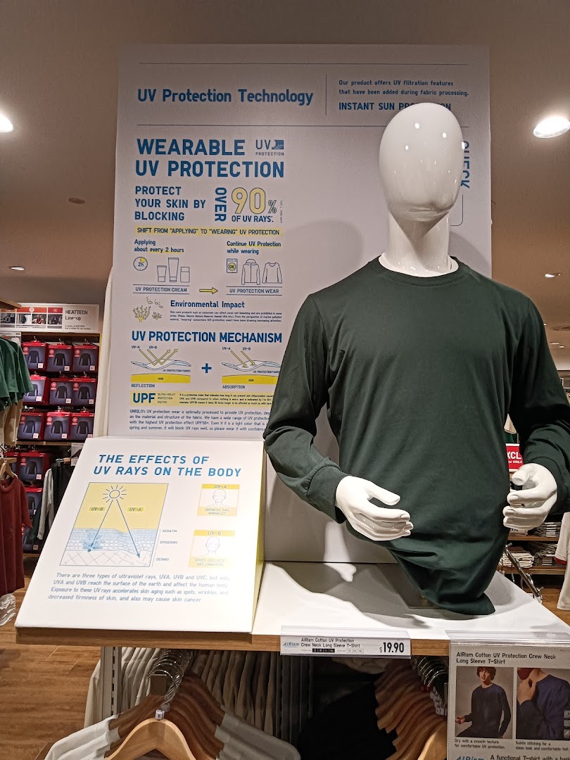 A mannequin displays UNIQLO's AIRism UV Protection long-sleeve shirt with informational signage.