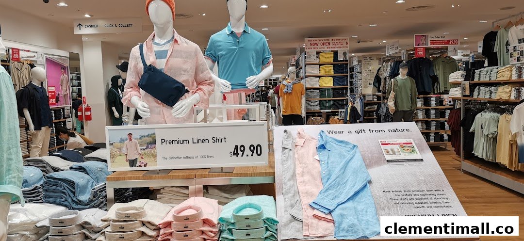 An interior view of UNIQLO, showcasing mannequins, folded apparel displays, and promotional signage for linen shirts.