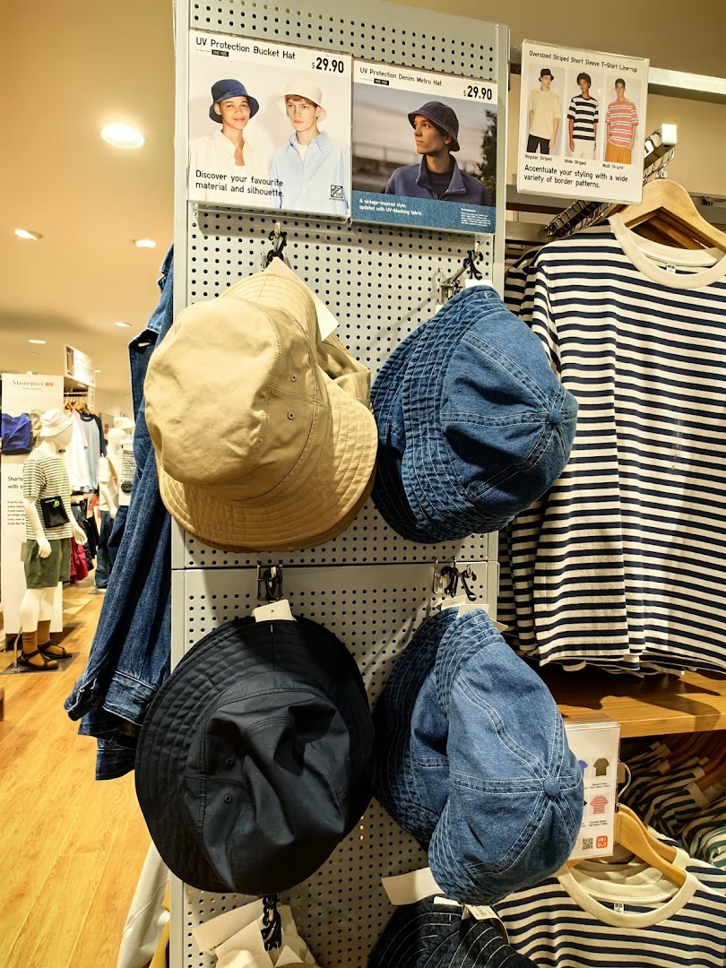 An in-store display at UNIQLO featuring UV protection hats and striped t-shirts.