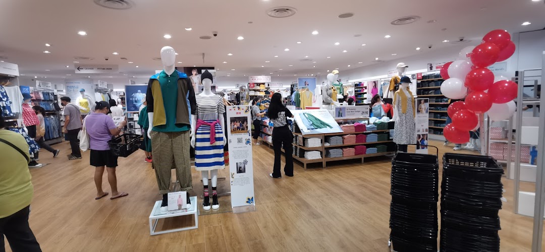 An interior view of a UNIQLO store with customers browsing clothing displays and mannequins.