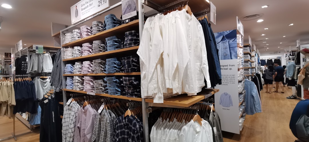 An interior view of UNIQLO, showcasing neatly displayed shelves of shirts and various apparel.