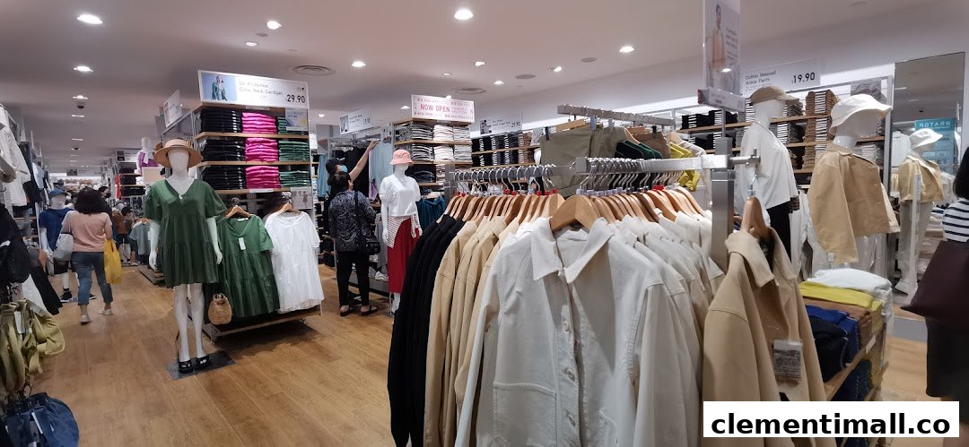 An interior view of UNIQLO, showcasing various clothing displays, mannequins, and shoppers browsing apparel.