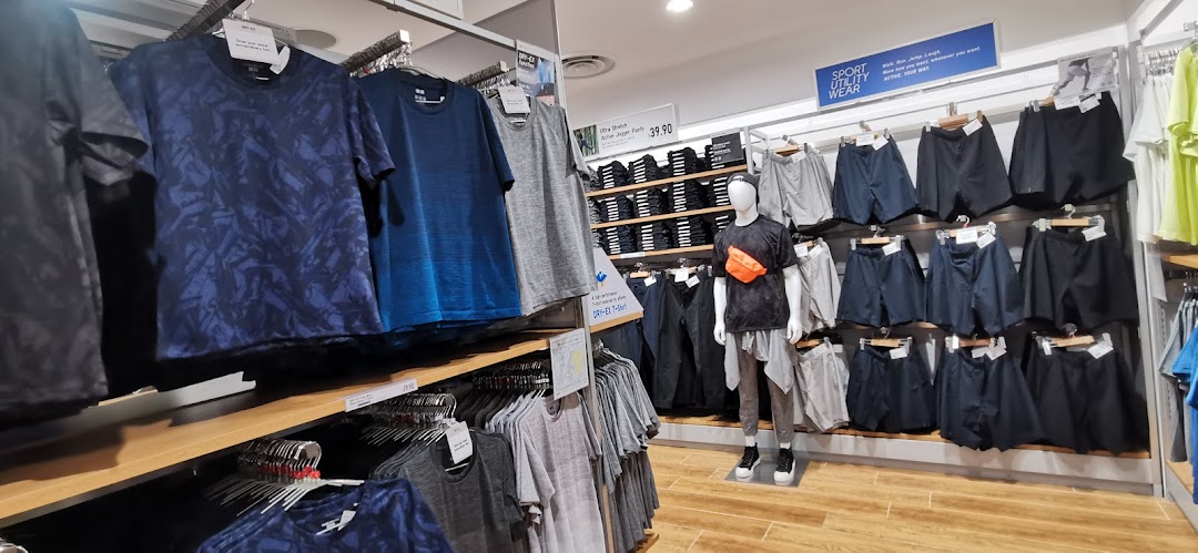 An interior view of UNIQLO showcasing a range of men's activewear and casual apparel on racks and a mannequin.