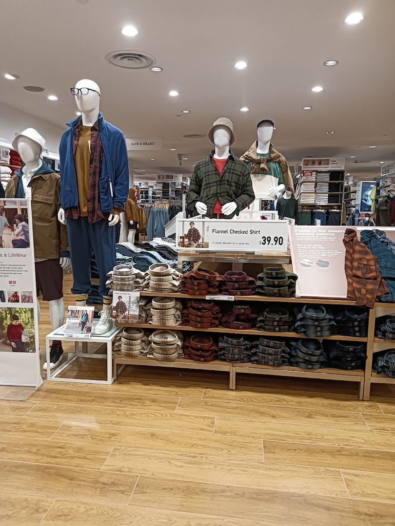 Mannequins display casual wear and flannel shirts inside a well-lit UNIQLO store.