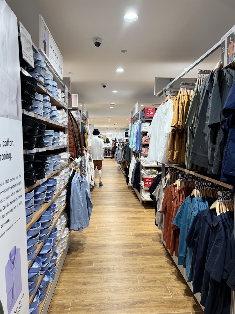 An interior view of UNIQLO, showcasing aisles of neatly displayed clothing and a wide selection.