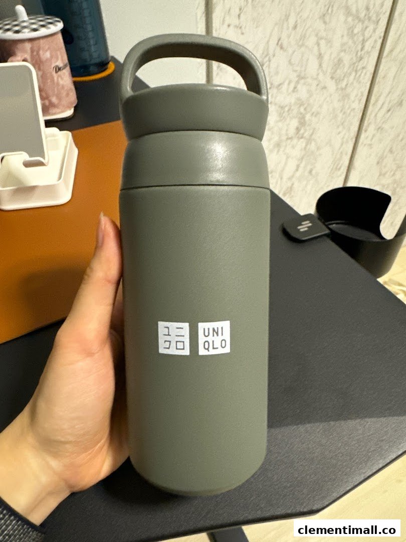 A hand holds a grey UNIQLO branded water bottle with a handle.