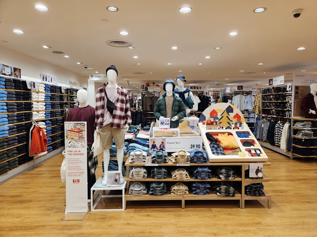 Interior view of UNIQLO showcasing clothing displays, mannequins, and neatly folded apparel.