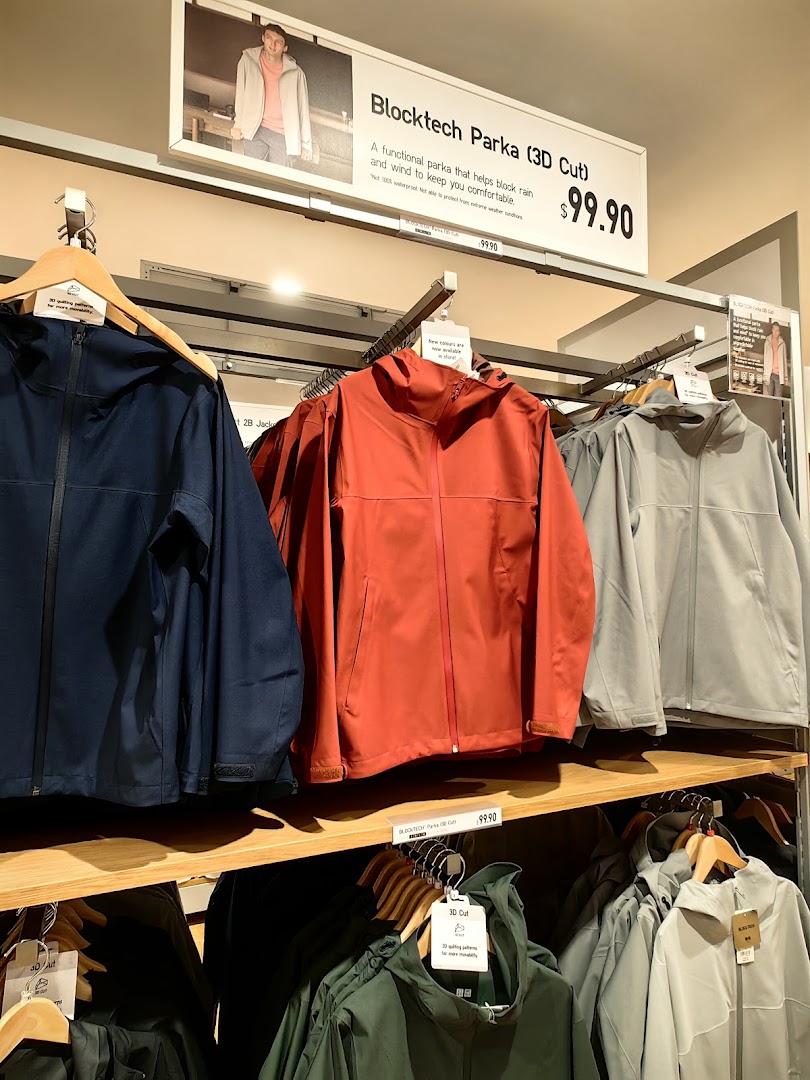UNIQLO's Blocktech Parkas on display with a promotional sign detailing features and price.