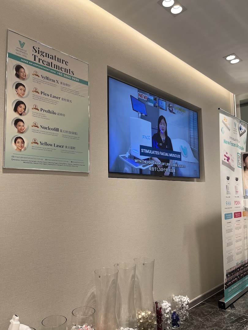 A display board showcasing V Medical Aesthetics' signature treatments and a promotional video.